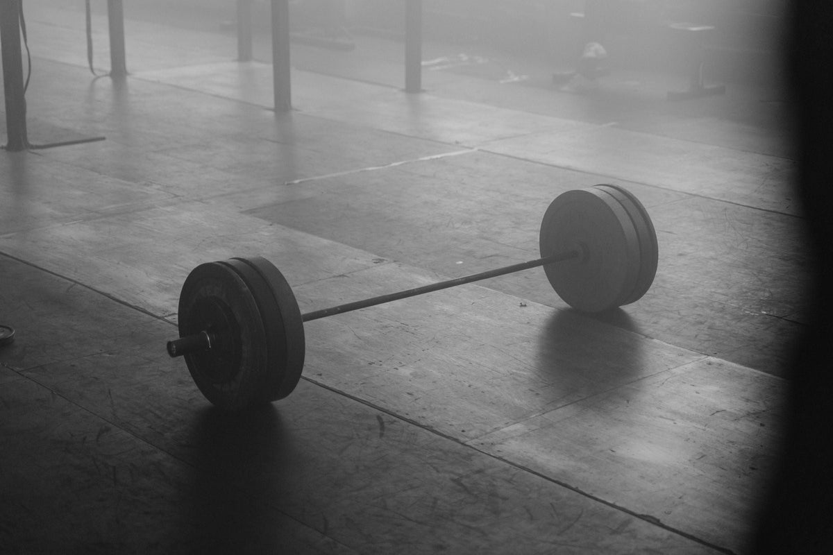 A loaded barbell resting on a dim, empty gym floor, for an article on the best time to take pre-workout