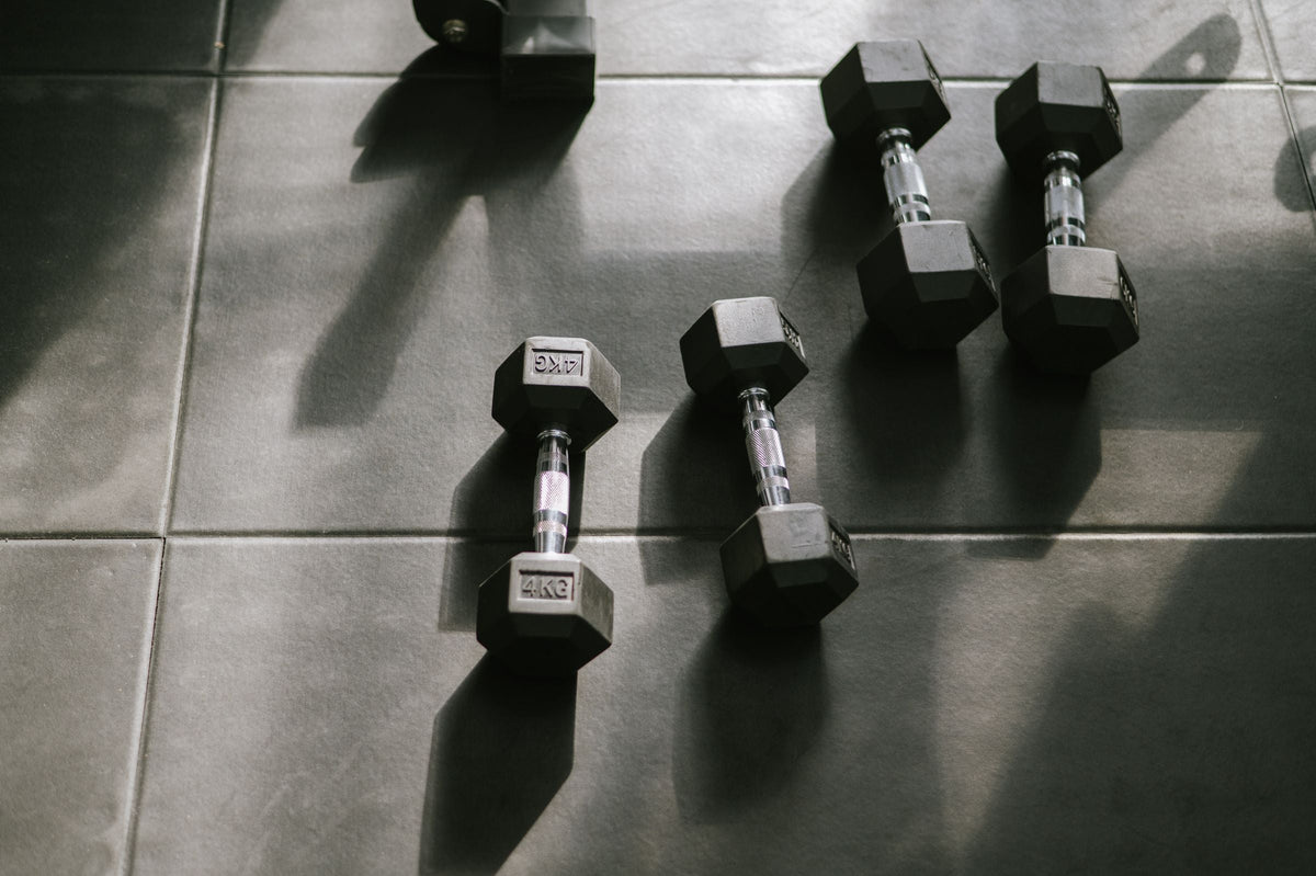 Hex dumbbells on a dark gym floor in low side light, for an article on taking ashwagandha and creatine together