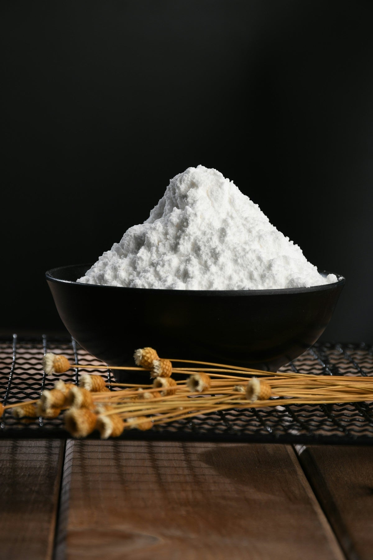 A heaped bowl of fine white powder on a dark table, for an article on how much creatine per day