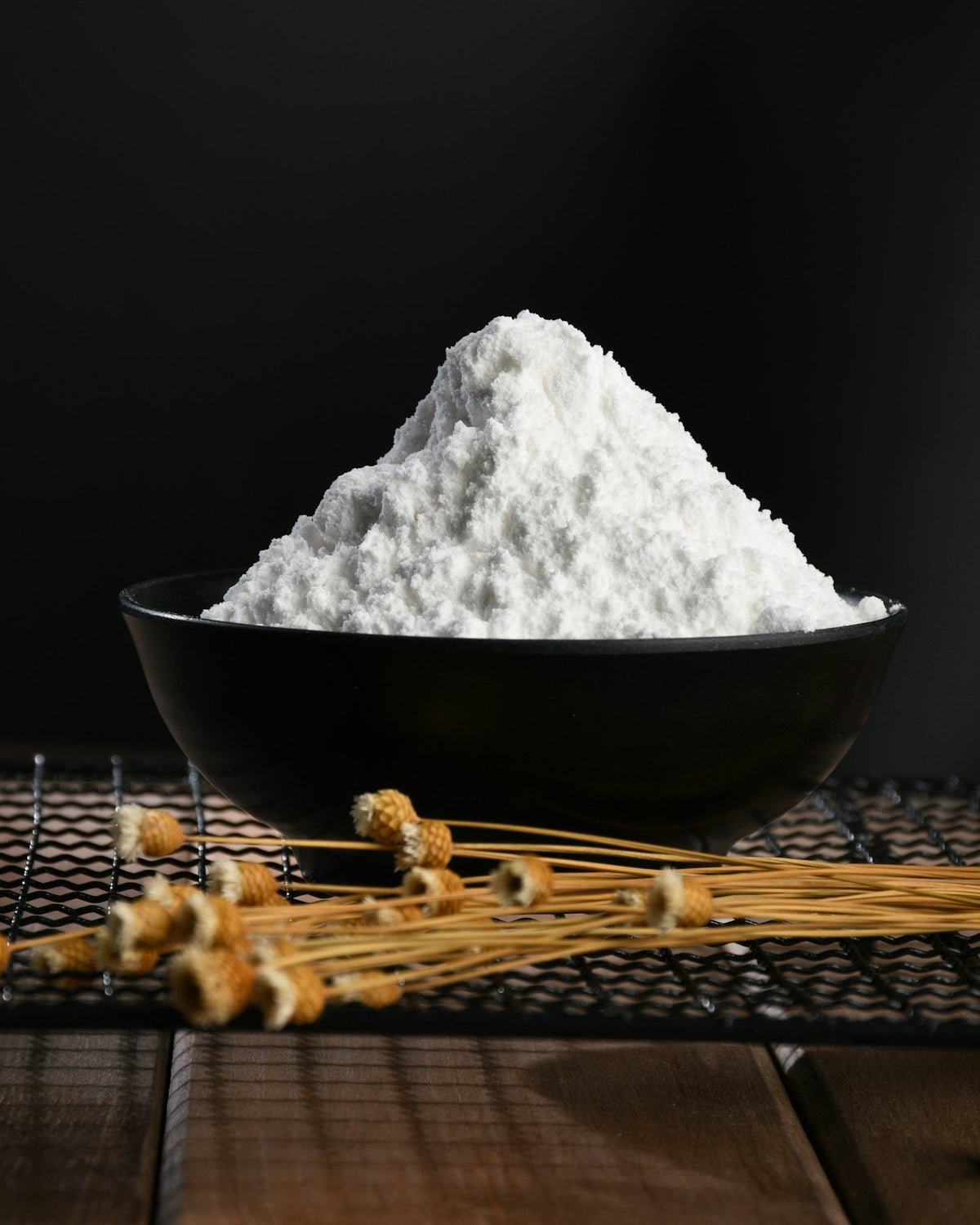 A mound of fine white creatine monohydrate powder in a black bowl