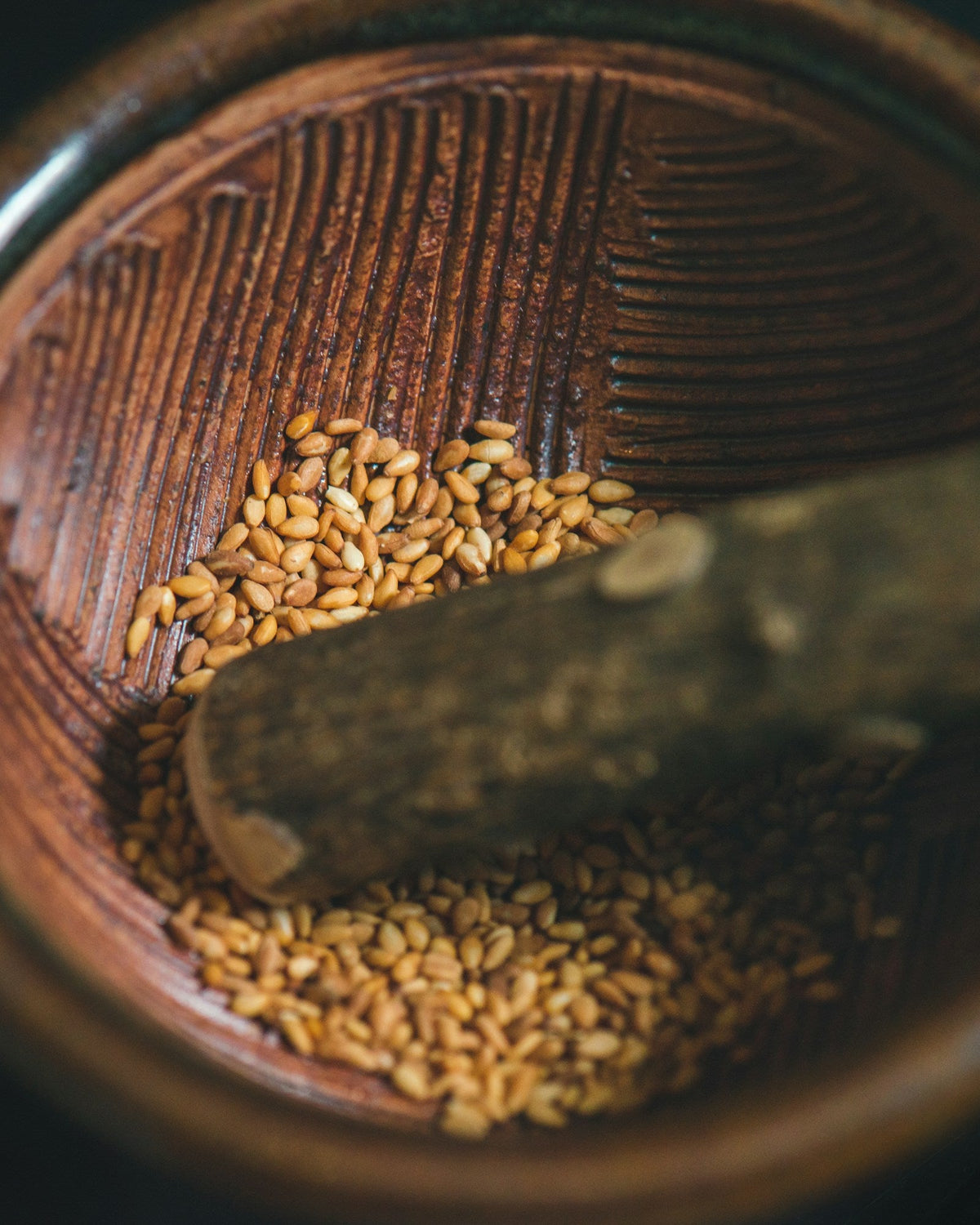 Golden fenugreek seeds in a wooden mortar with a pestle