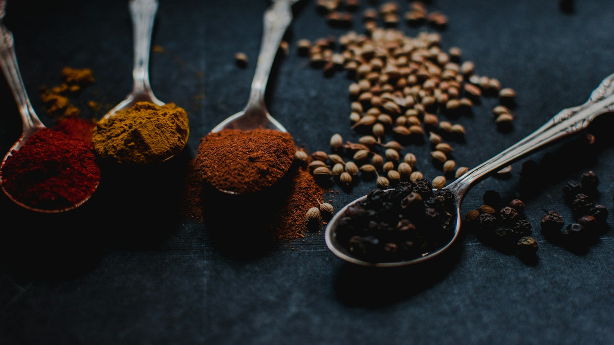 Ground roots, spices and seeds laid out on a dark surface, representing ashwagandha and tongkat ali