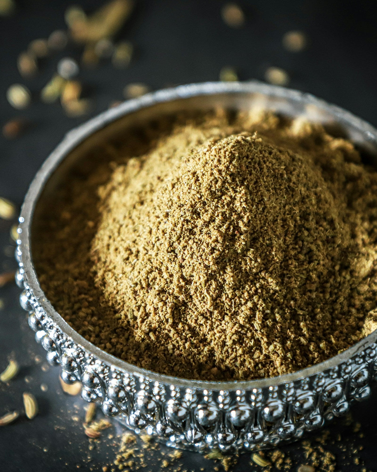 Finely ground herbal root powder heaped in a silver bowl on a dark surface, for an article on ashwagandha side effects