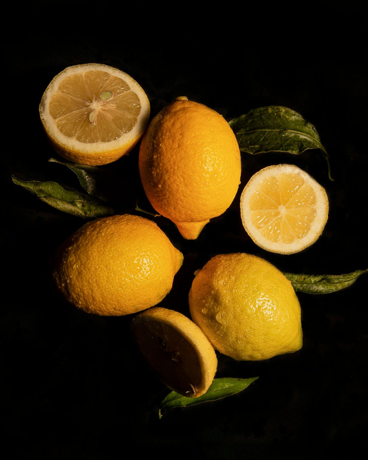 Whole and halved lemons with leaves on a black background, for an article on electrolytes vs. sports drinks