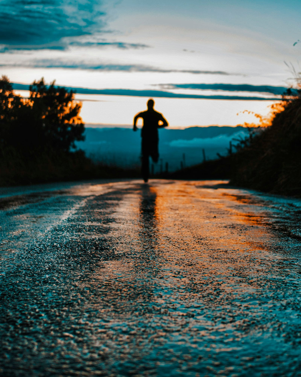 A runner in silhouette on a wet road at dawn
