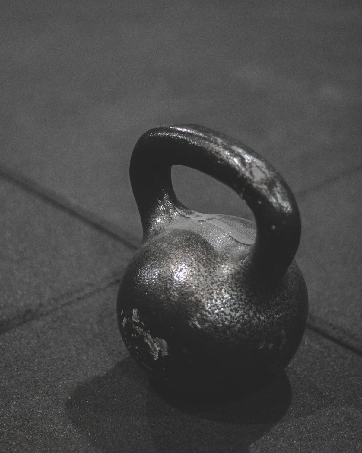 A worn iron kettlebell on a dark gym floor, for an article on whether paraxanthine is safe