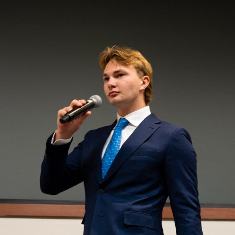 Ben Tybur, MAXIS co-founder, speaking into a microphone at a presentation
