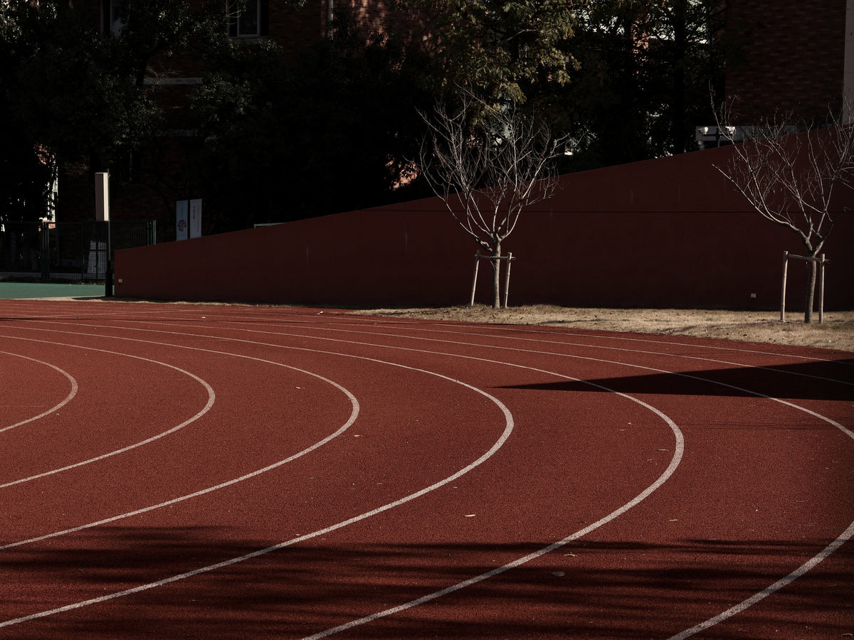 The curve of a red running track in late-afternoon light
