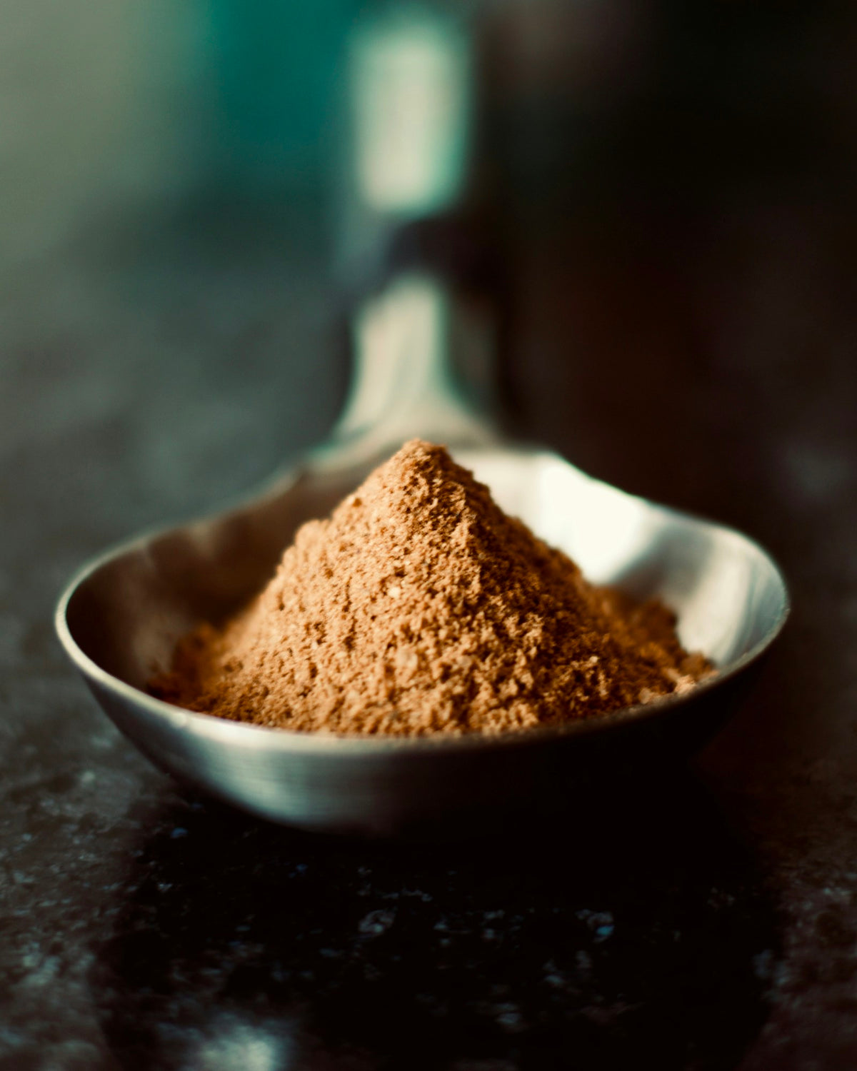 A spoonful of fine cocoa powder in low light