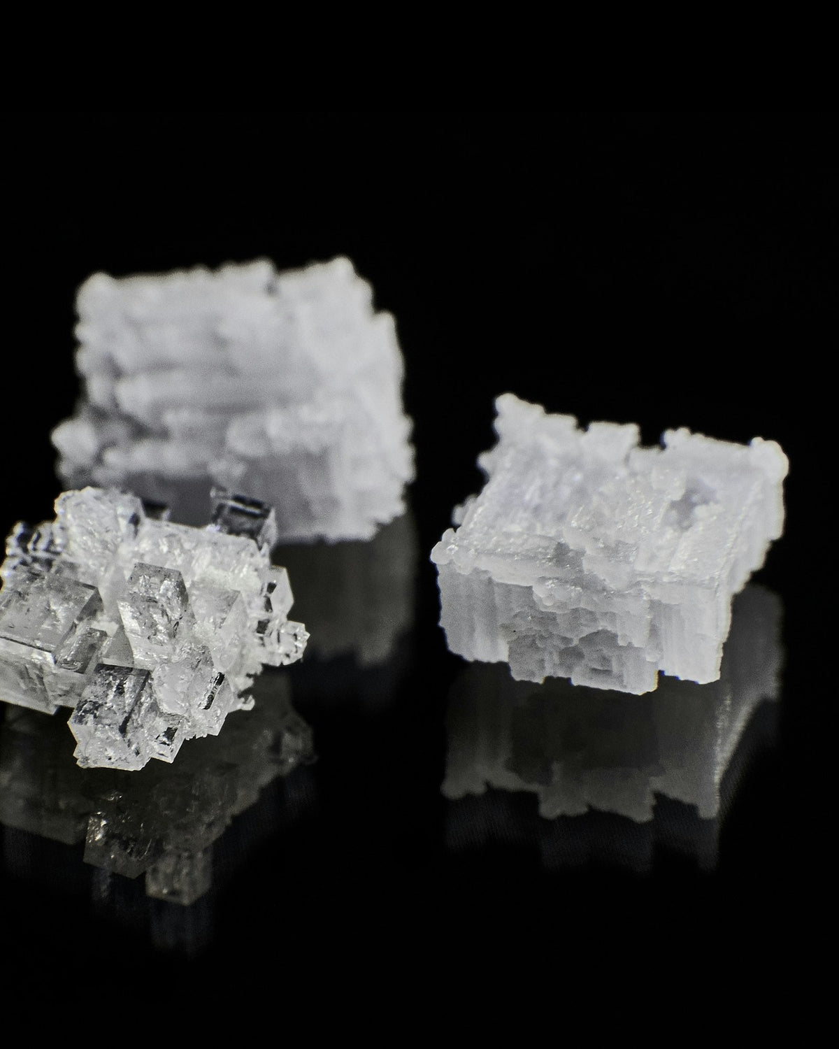 White mineral crystals on a black reflective surface
