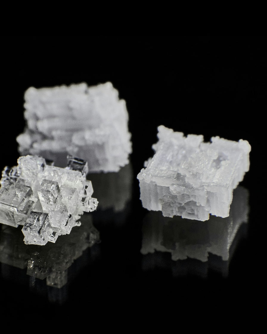 White mineral crystals on a black reflective surface