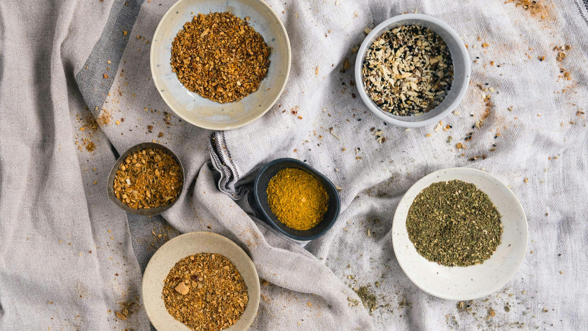 Small bowls of ground spices and seeds on natural linen